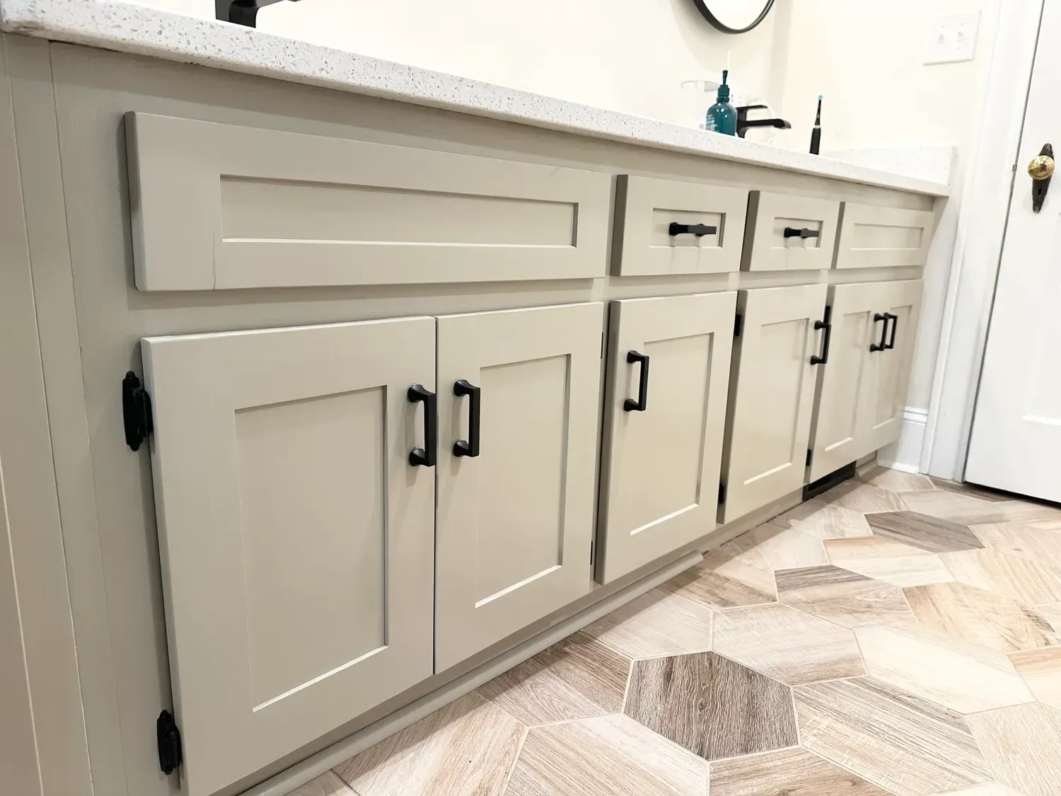 White bathroom vanity with cabinet doors, drawers, and a light countertop against a tiled floor.