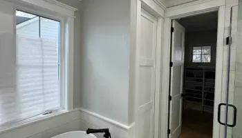 Bright hallway with white walls, window bench, and open doorway to a closet with shelving.