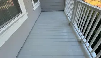 Empty gray front porch with white railing and window