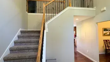Carpeted staircase beside a white half wall and open hallway in a home interior