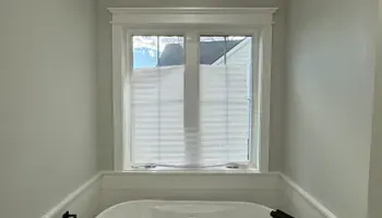 Small bathroom with a frosted window above a bathtub and white trim.