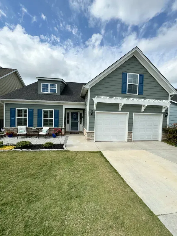 Suburban house with gray siding, blue shutters, a two-car garage, and a front lawn under a cloudy sky