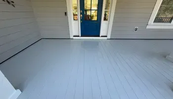 Freshly painted gray front porch with a blue front door and white trim