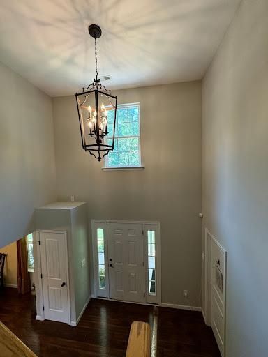 Two-story foyer with hanging lantern, white walls, dark wood floors, and front door below a window.
