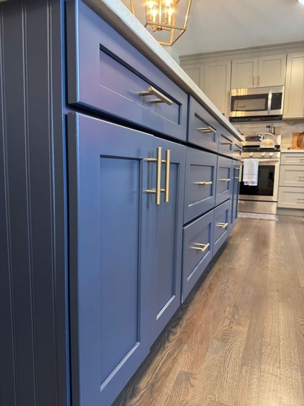 Blue kitchen cabinets with gold handles in a modern kitchen interior.