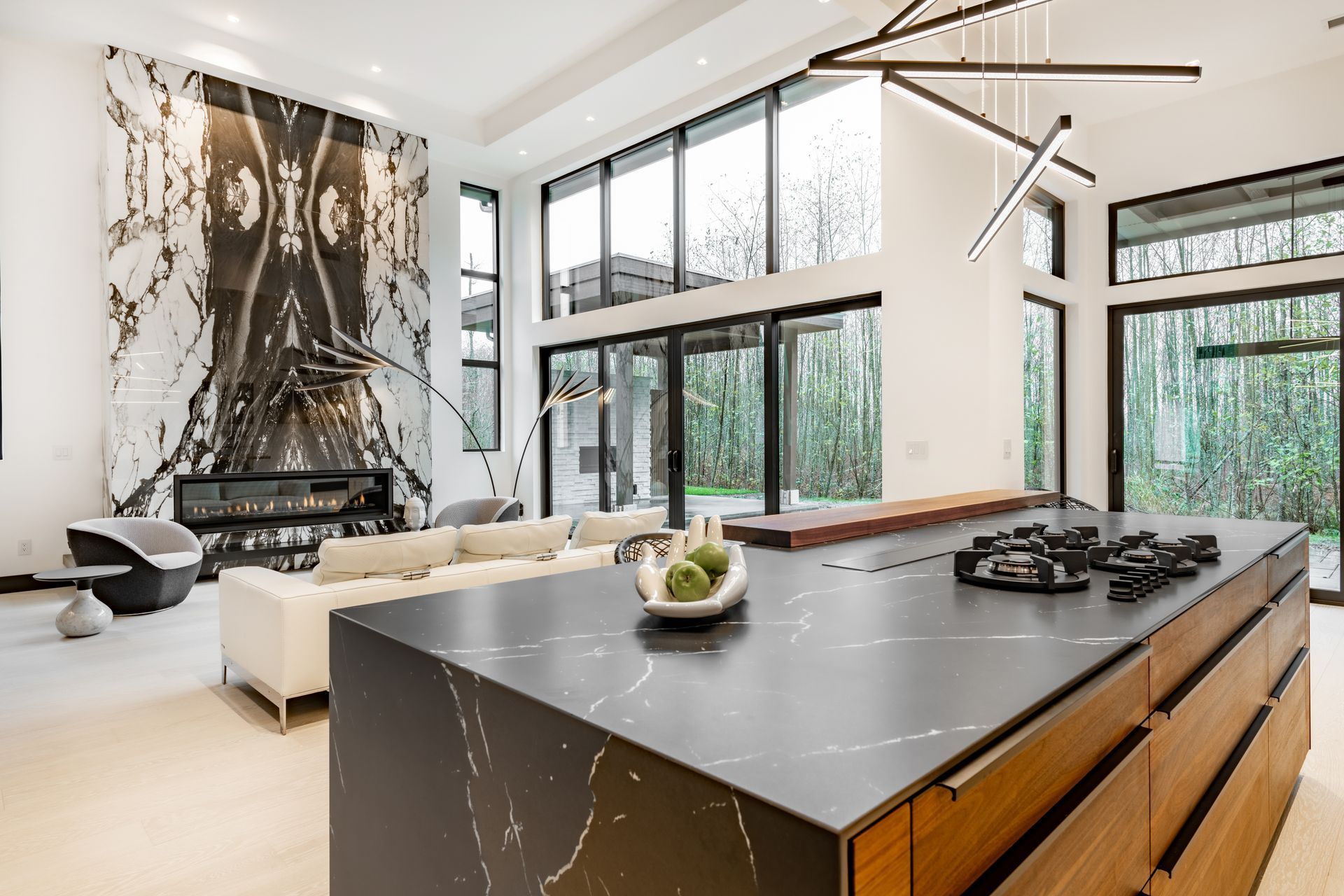 Modern open-concept living room and kitchen with marble island, large windows, and abstract wall art