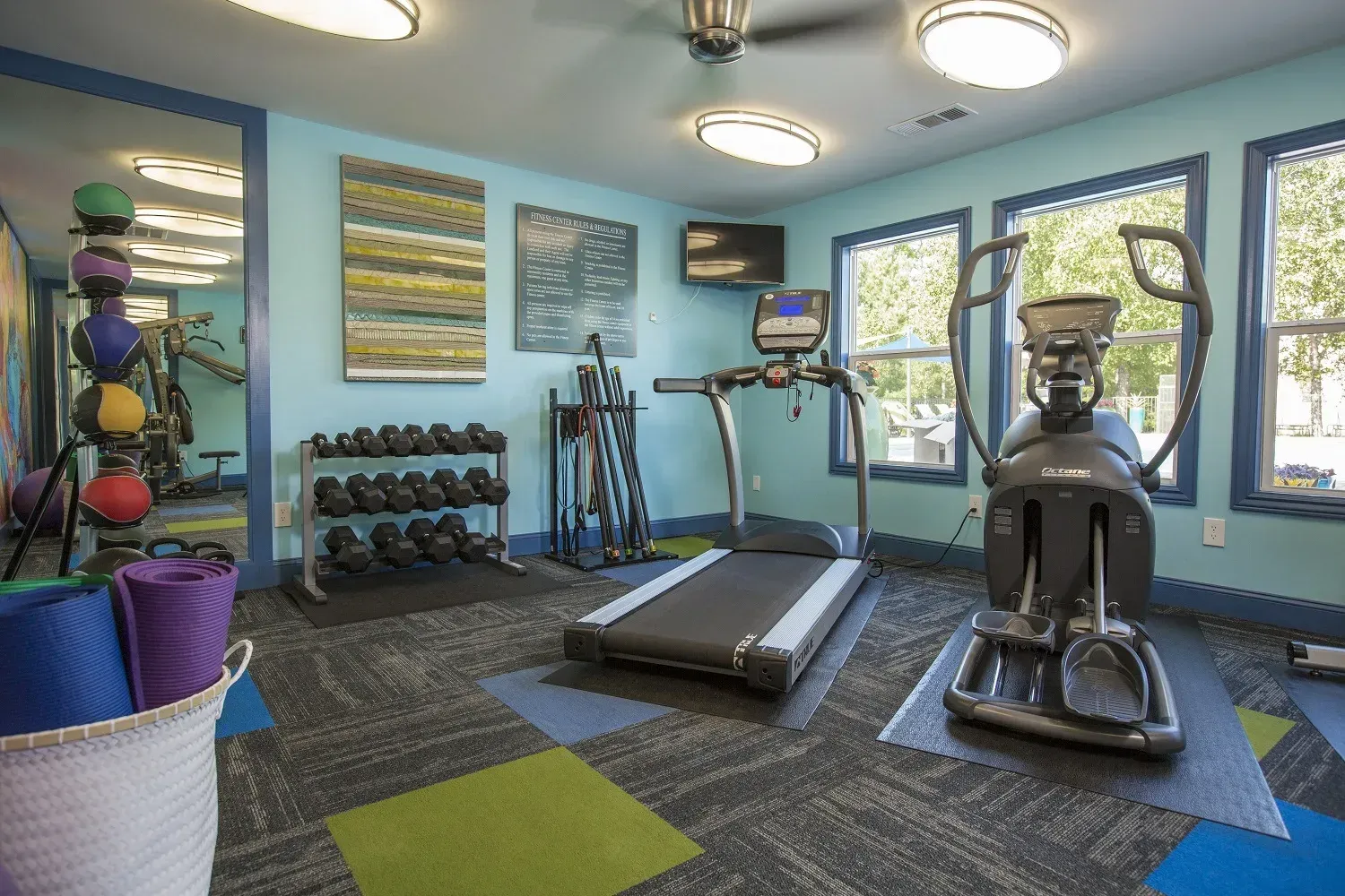 Photo of a community gym, showing treadmills, dumbells and more