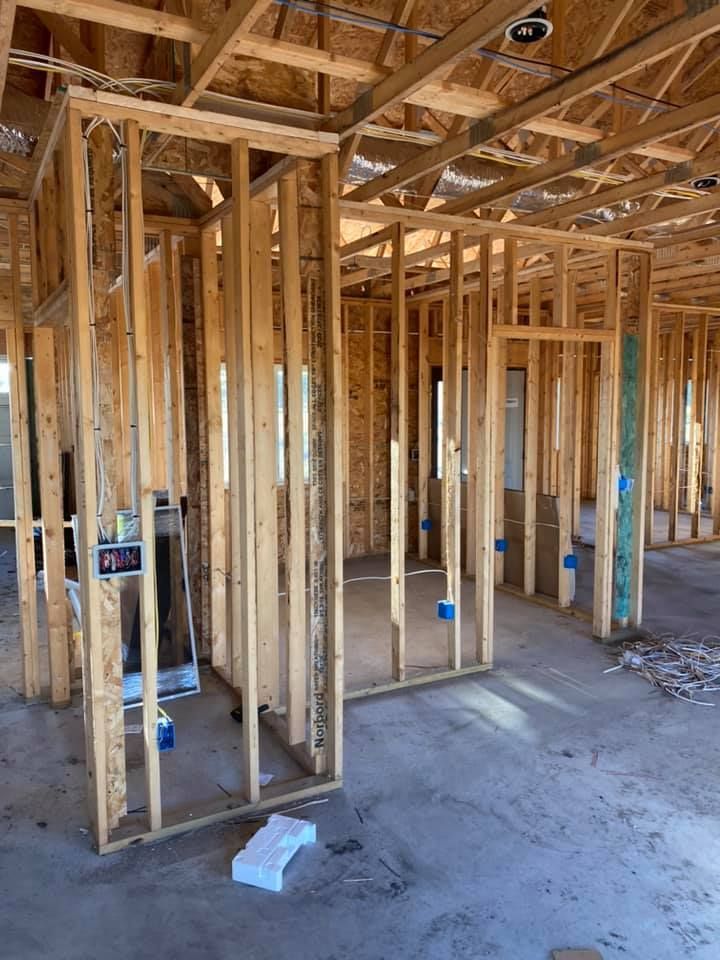 Interior wood framing of a house under construction with electrical wiring and blue outlet boxes.