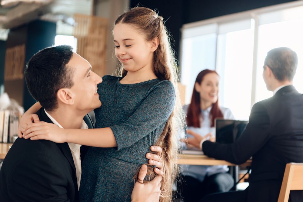 A man is holding a little girl in his arms in an office.