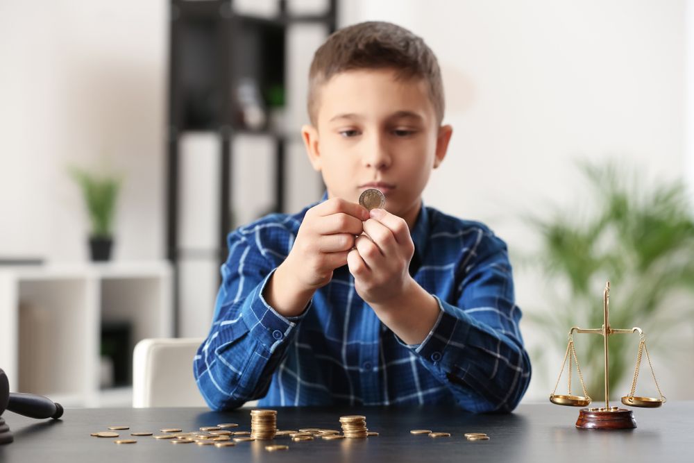 A young boy is sitting at a table counting coins.