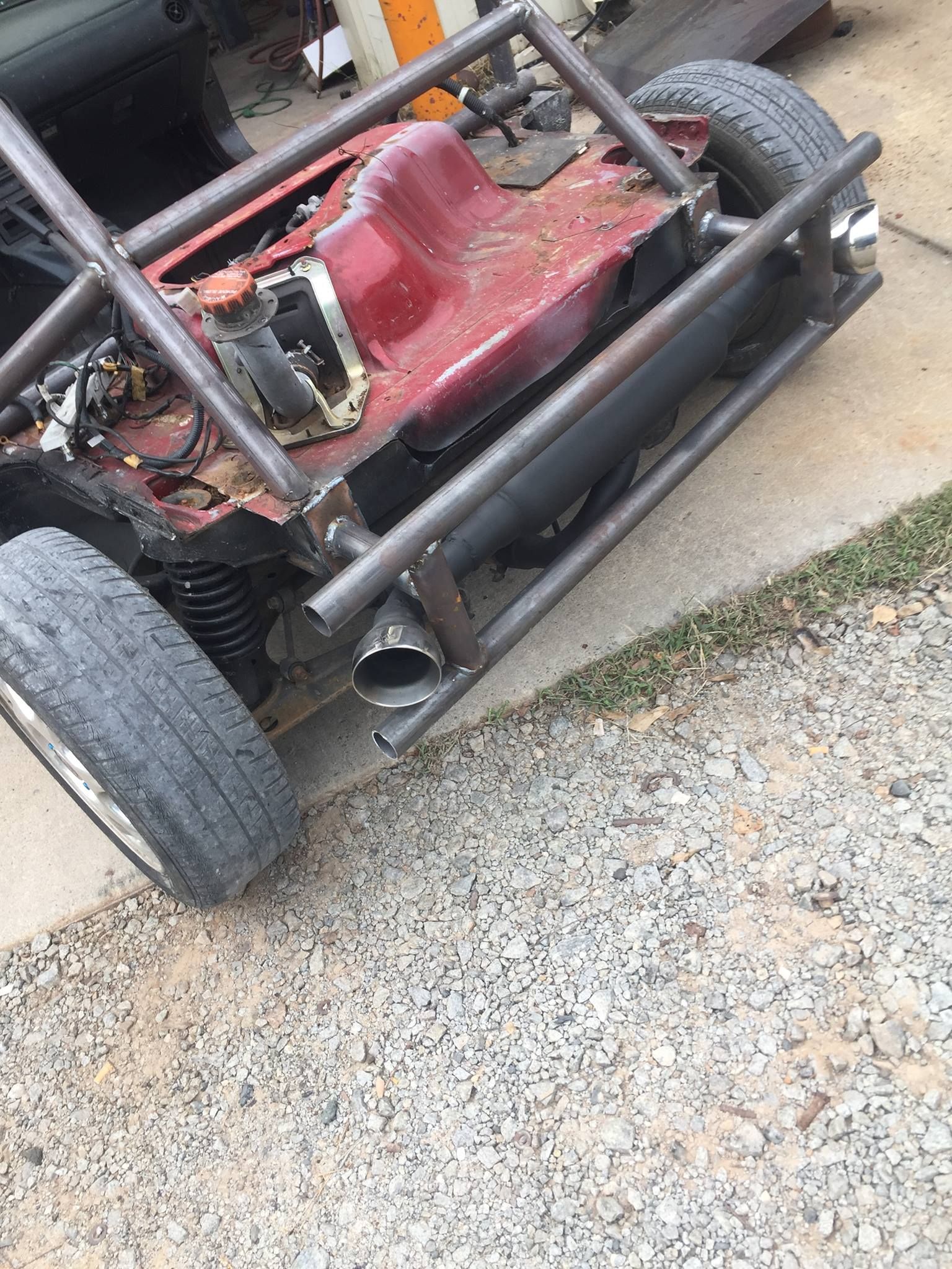 A red buggy is parked on a gravel road.