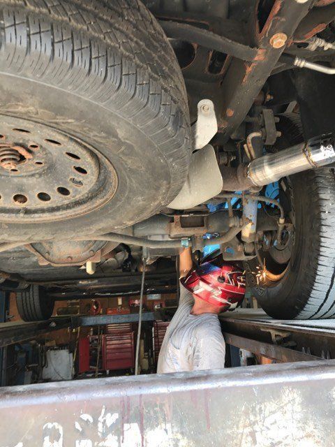 A man is working under a car in a garage.
