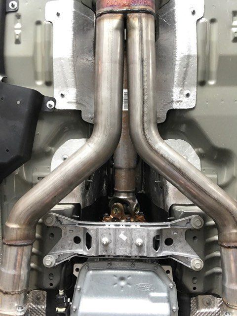 A close up of the underside of a car with exhaust pipes.
