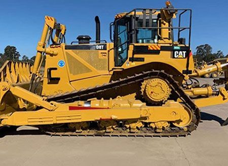 A yellow cat bulldozer is parked on the side of the road.
