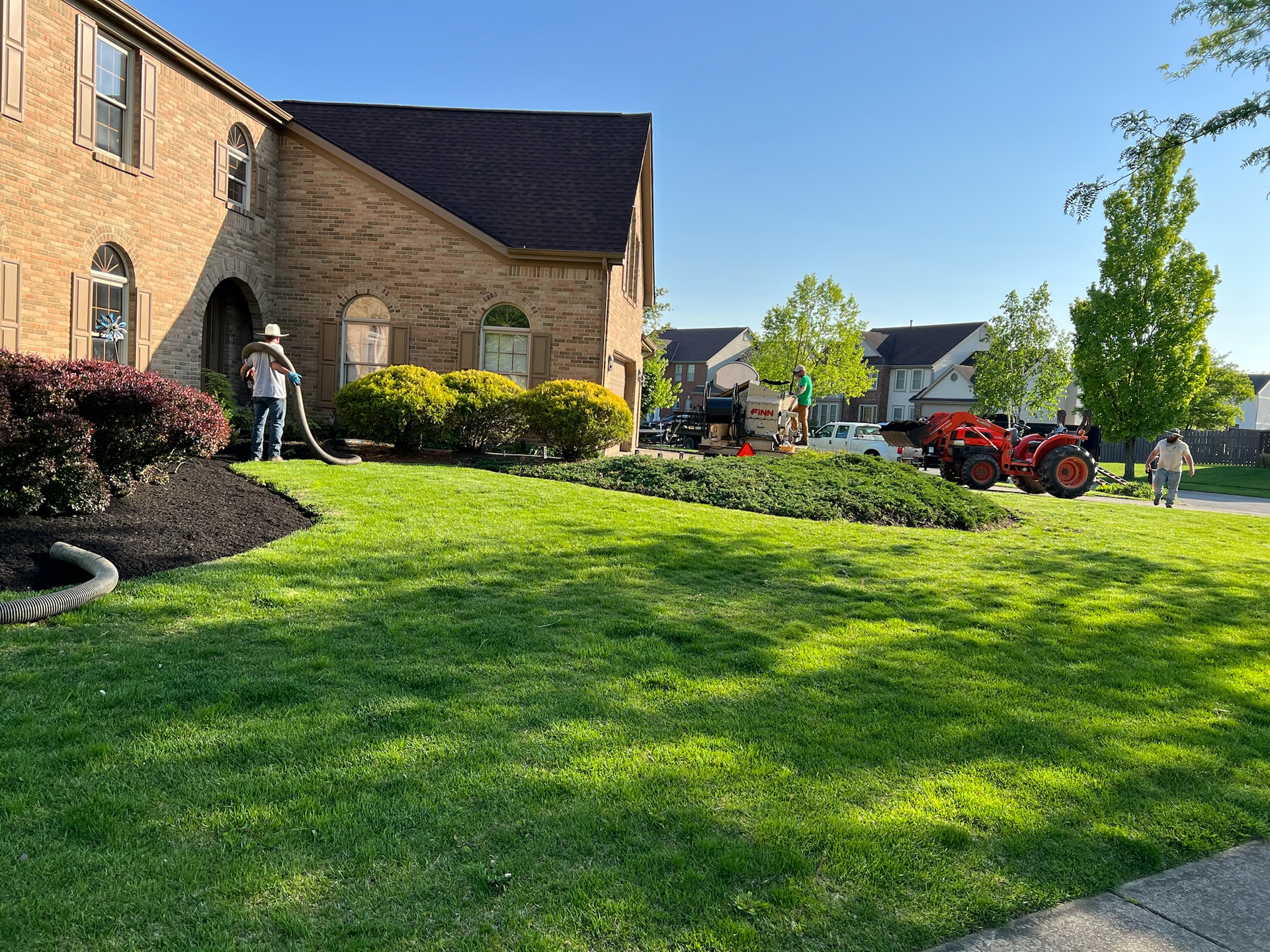 A tractor is parked in the grass in front of a house.