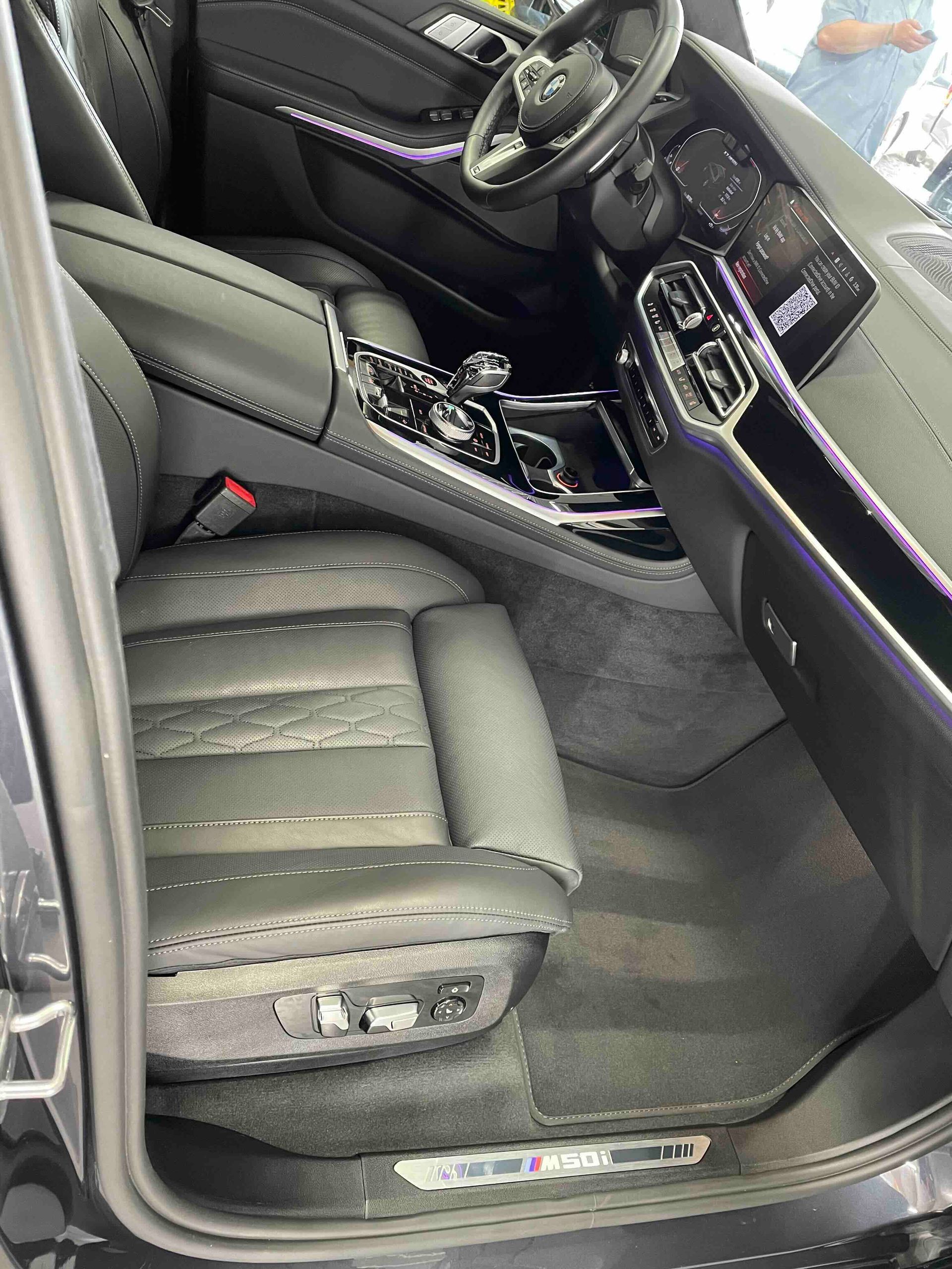 Black leather interior of a luxury car, showing driver's seat, dashboard, and floor details.