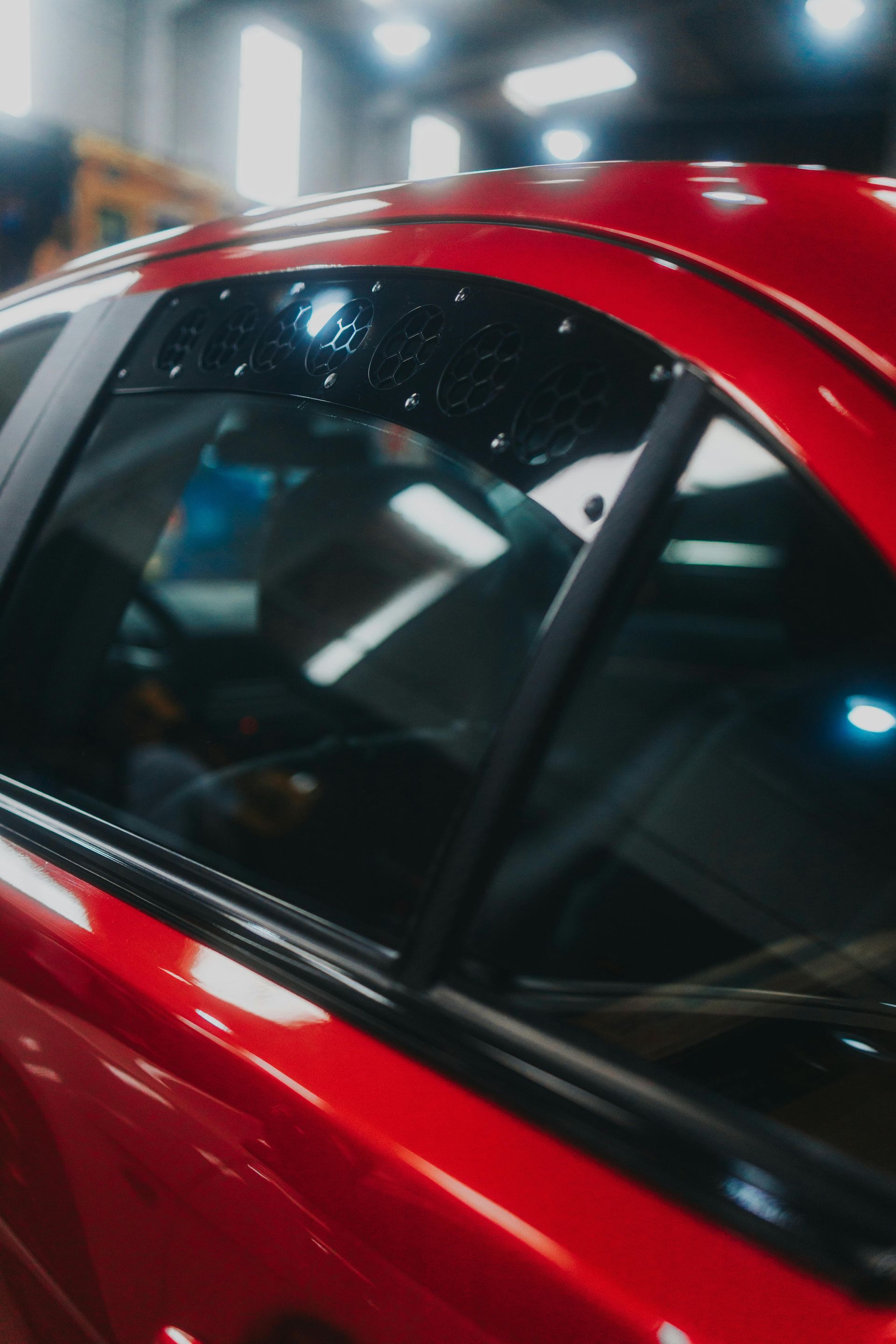 Red car side window with a black rain guard.