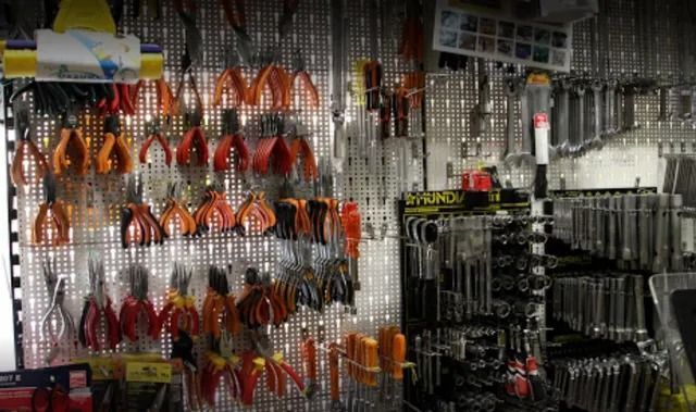 Pinze e utensili manuali di vario tipo appesi a uno scaffale espositivo in un negozio.