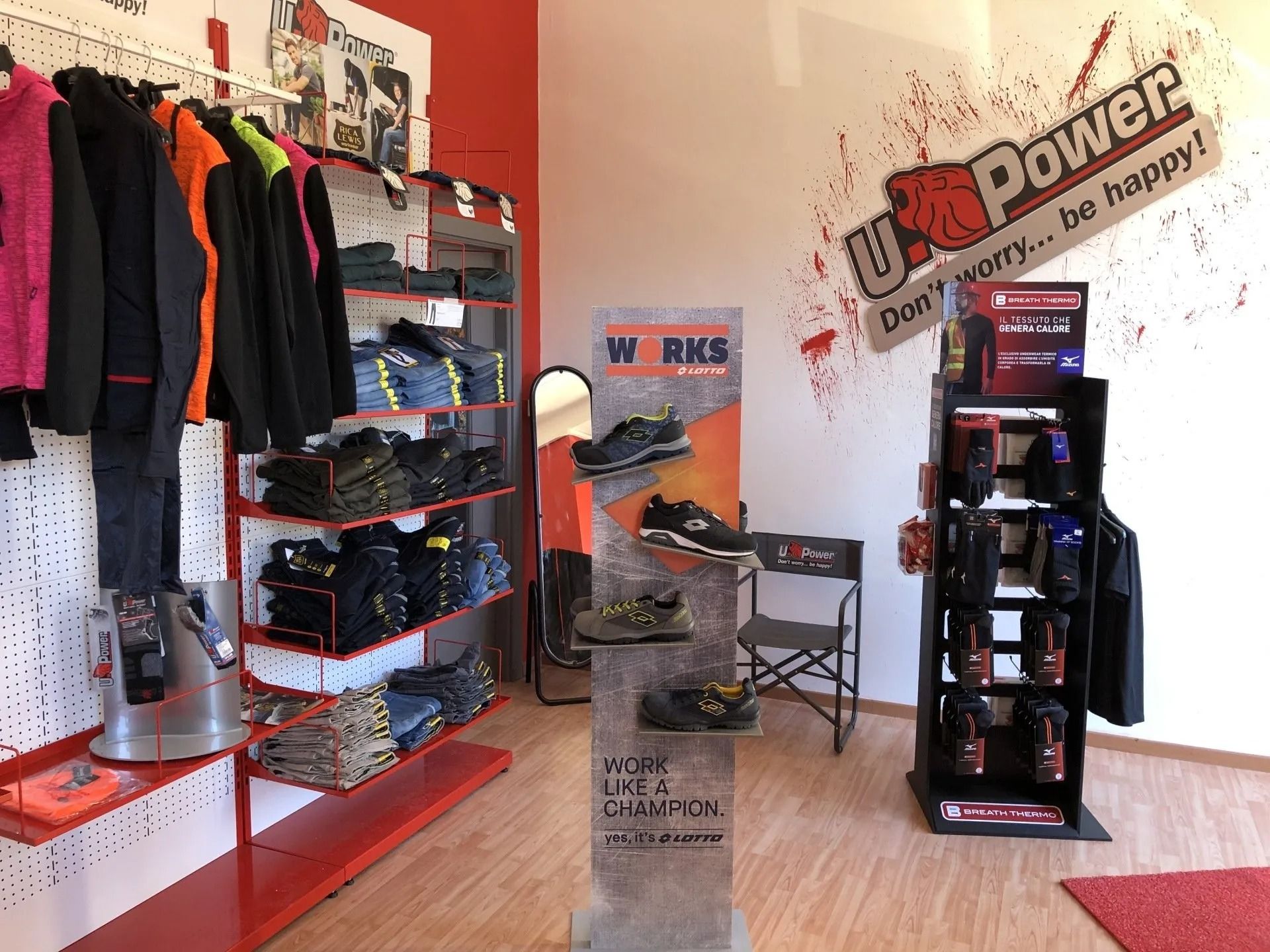 Interno di un negozio di abbigliamento sportivo con scaffali rossi, vestiti appesi e un display 