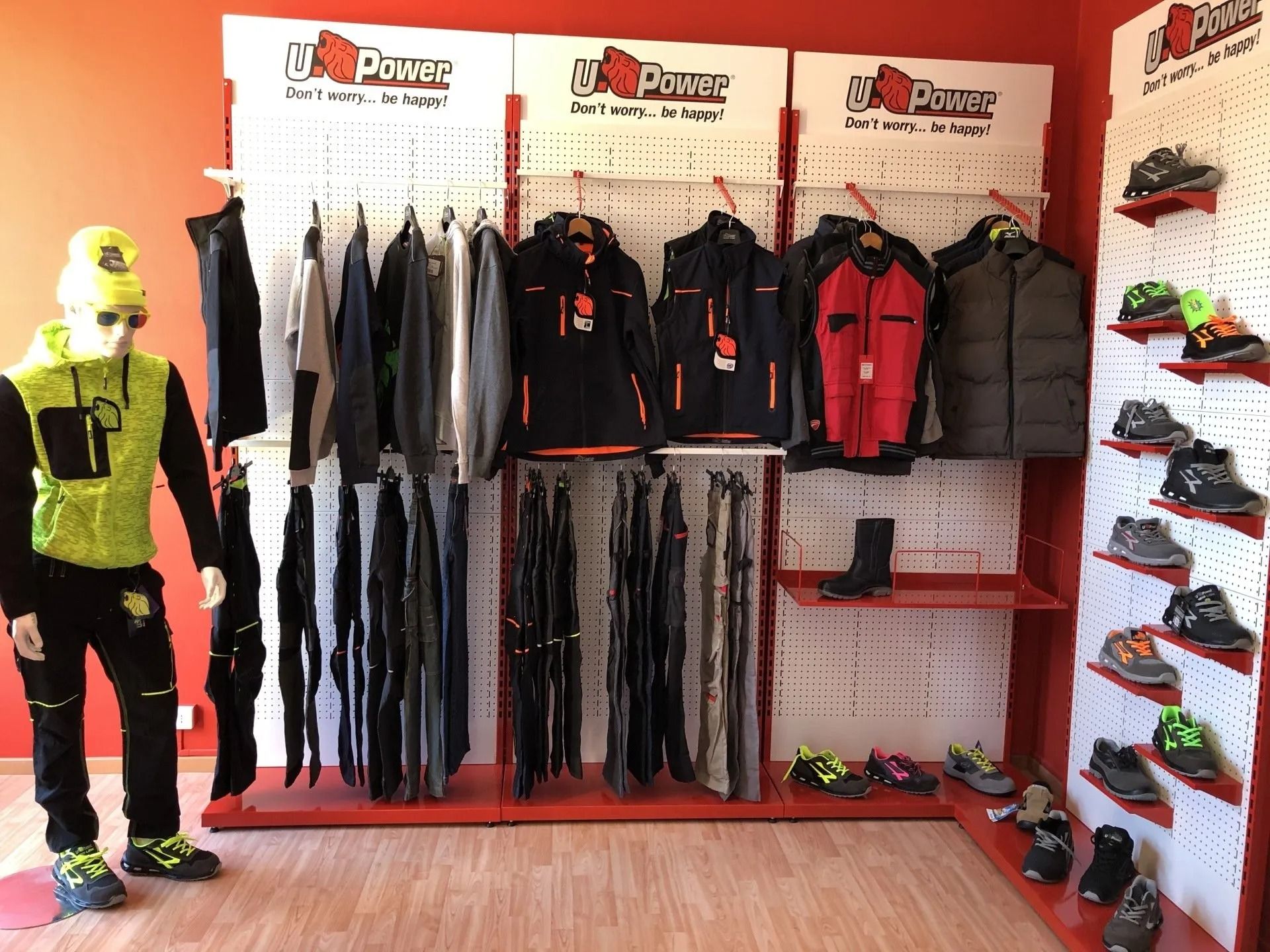 Esposizione di attrezzatura per attività all'aperto con giacche, pantaloni, stivali e manichino in un negozio al dettaglio.