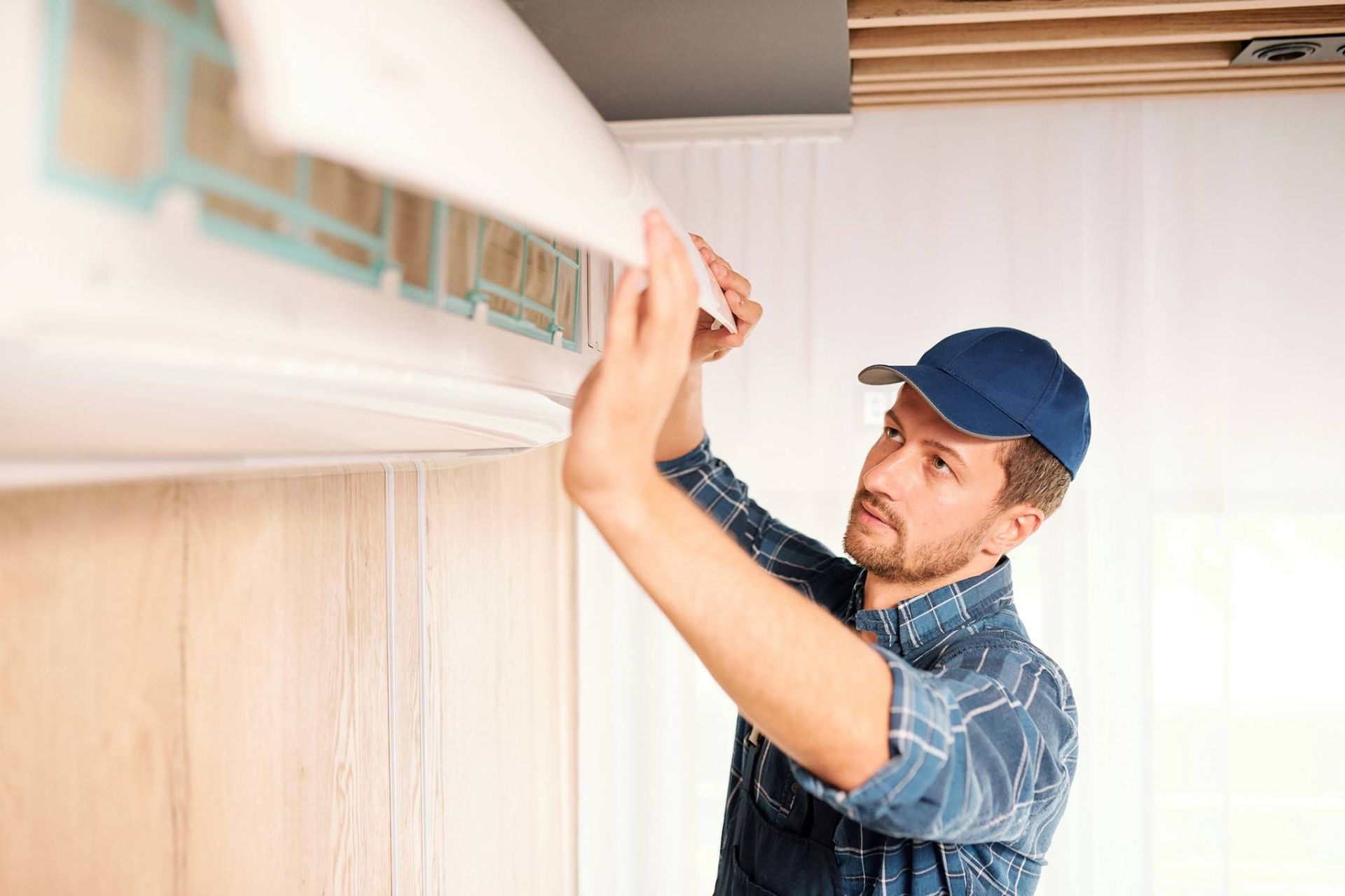 Technician installing a wall-mounted air conditioner indoors with a tool