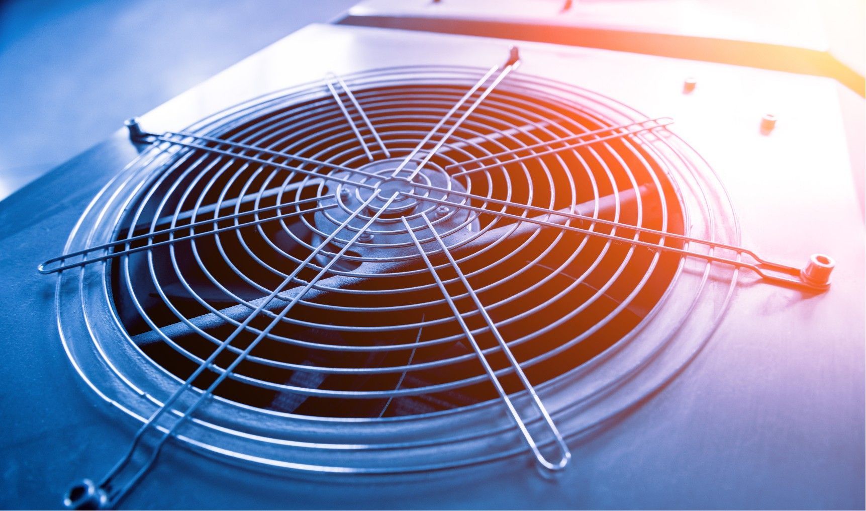Close-up of a metal fan grille lit in blue and orange on a tabletop