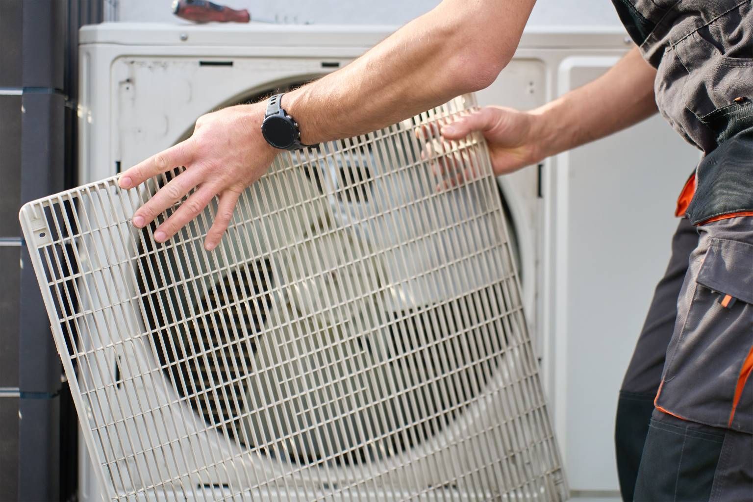 Person removing a white window air conditioner from a wall unit