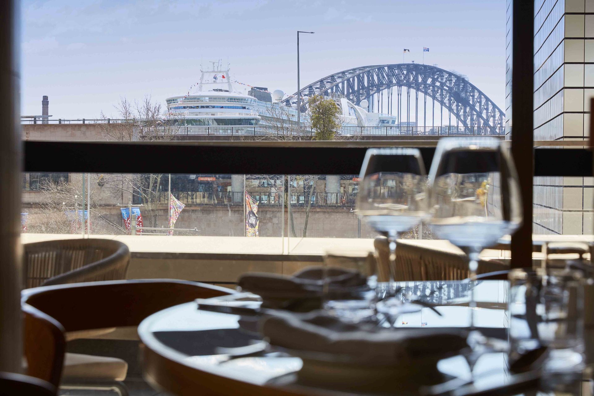 Empty restaurant with tables and chairs overlooking a city bridge through large windows