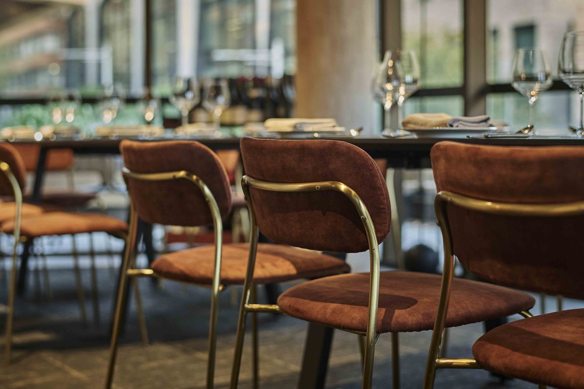 Empty restaurant chairs and set dining tables in a softly lit interior.