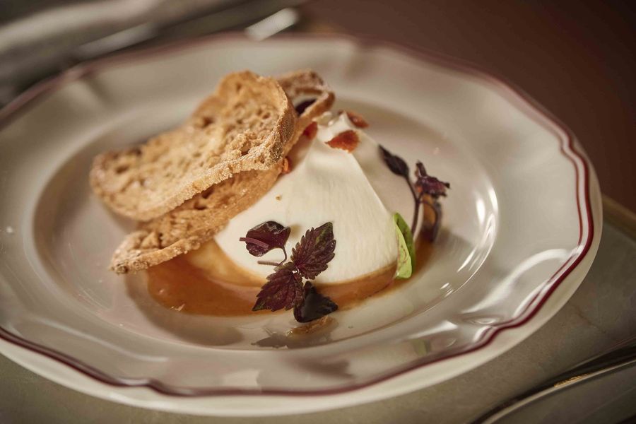 Plated dessert with cream, berry sauce, and biscotti on a white dish