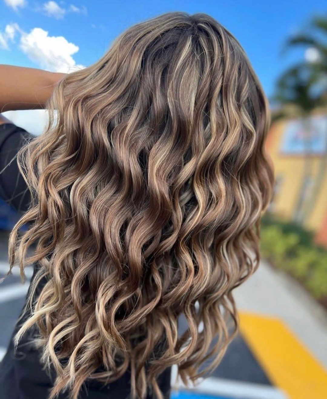 Wavy brown hair with blonde highlights, outdoors.