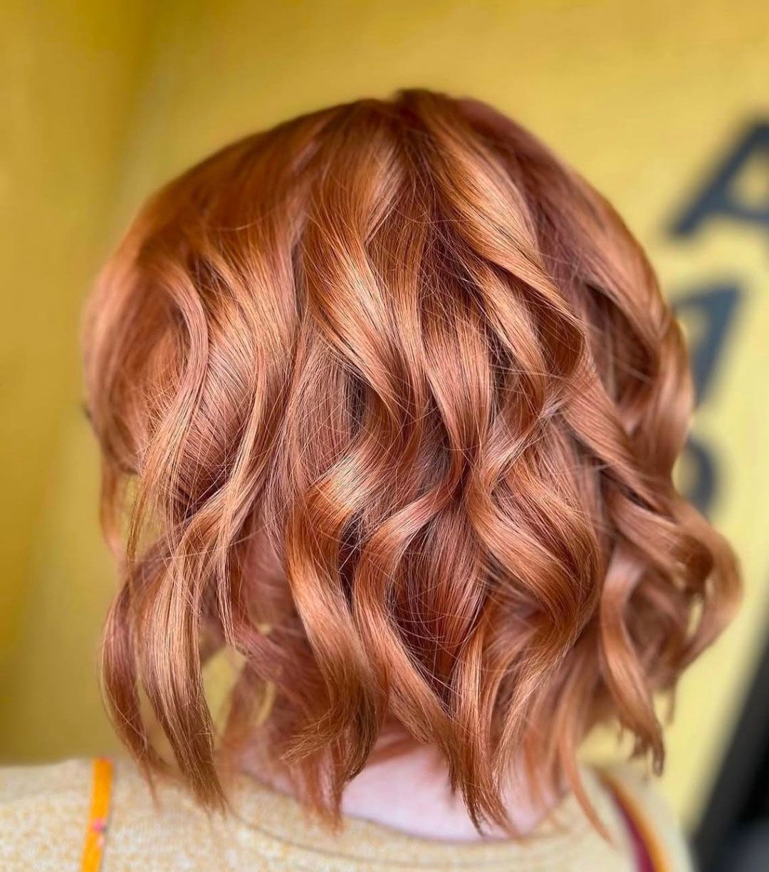 Copper-colored, wavy bob hairstyle with highlights.