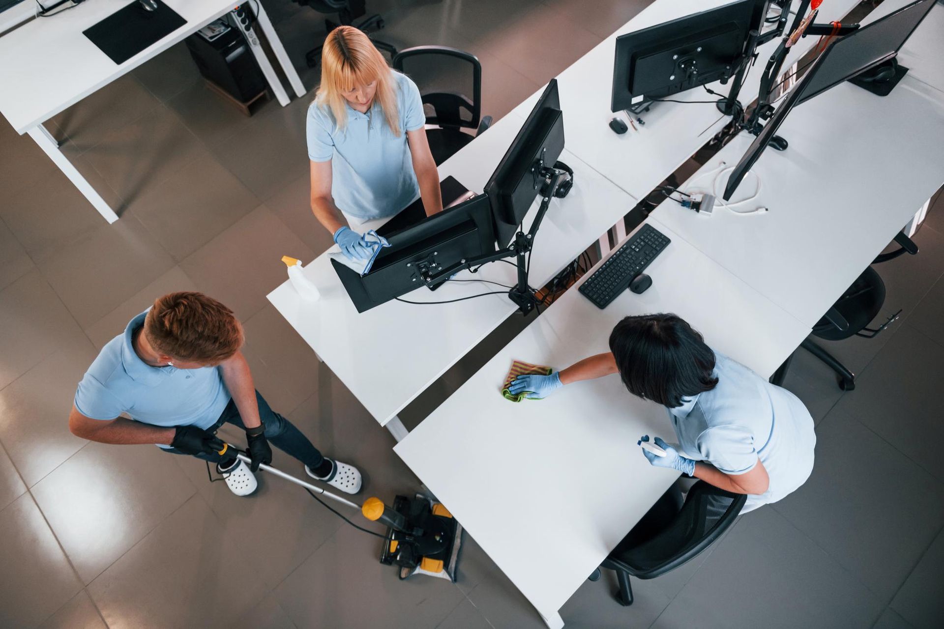 A group of people are cleaning desks in an office.