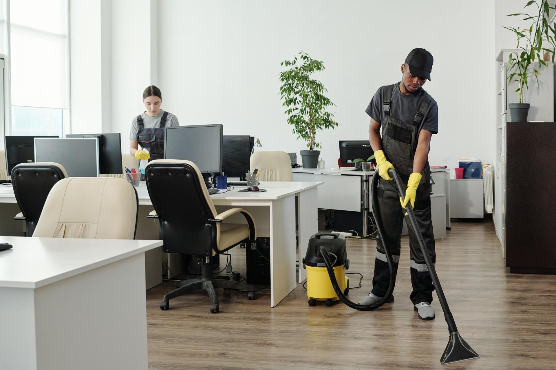 A man is cleaning the floor of an office with a vacuum cleaner.