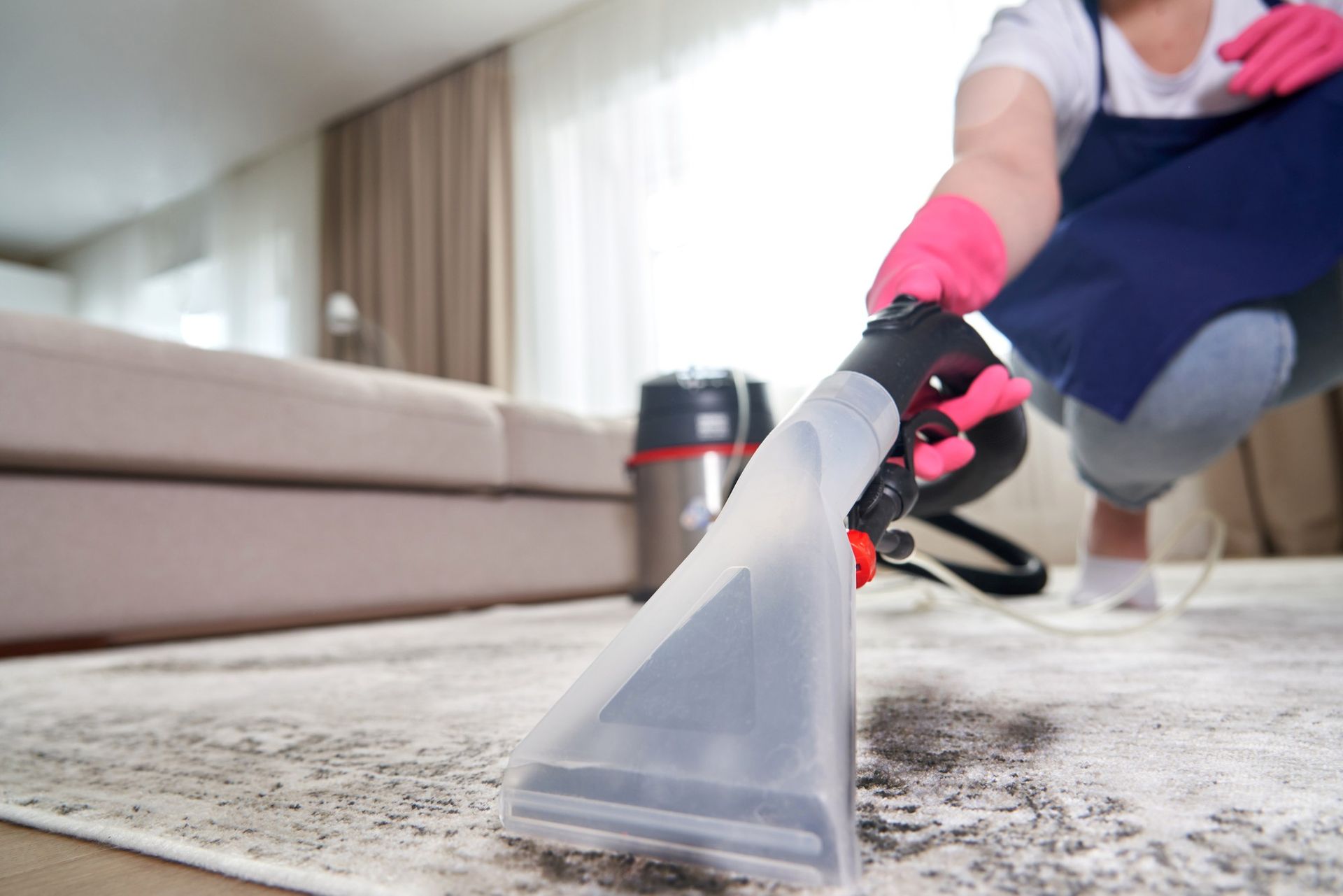 A woman is cleaning a rug with a vacuum cleaner in a living room.