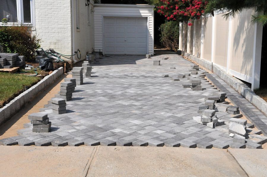 A brick driveway is being built in front of a house