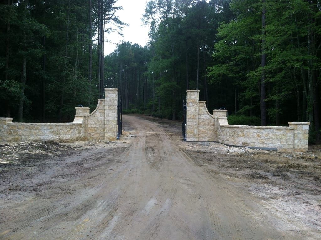 A dirt road with a stone wall on the side of it