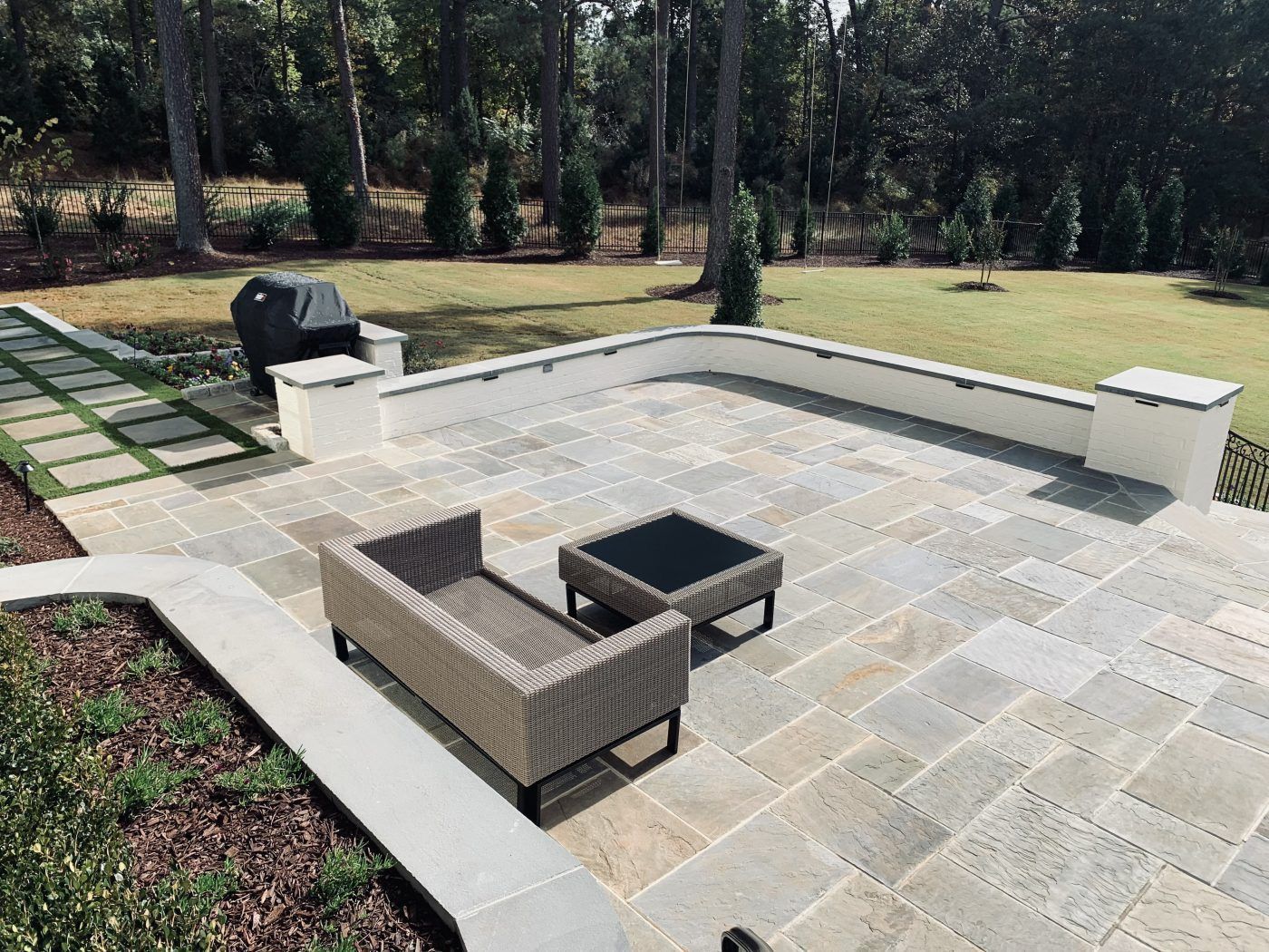 A patio with a couch, table and grill