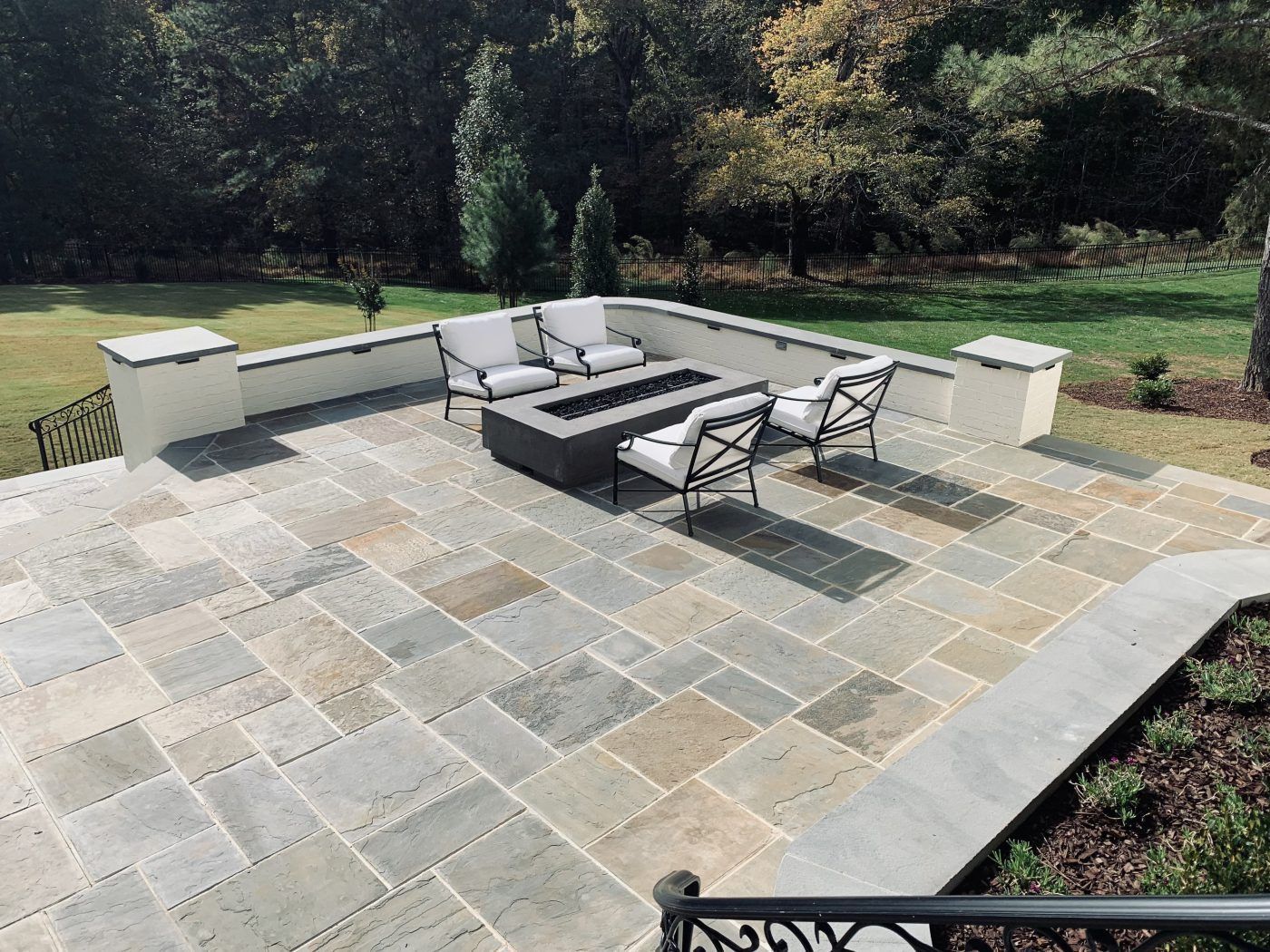A patio with a fire pit and chairs on it