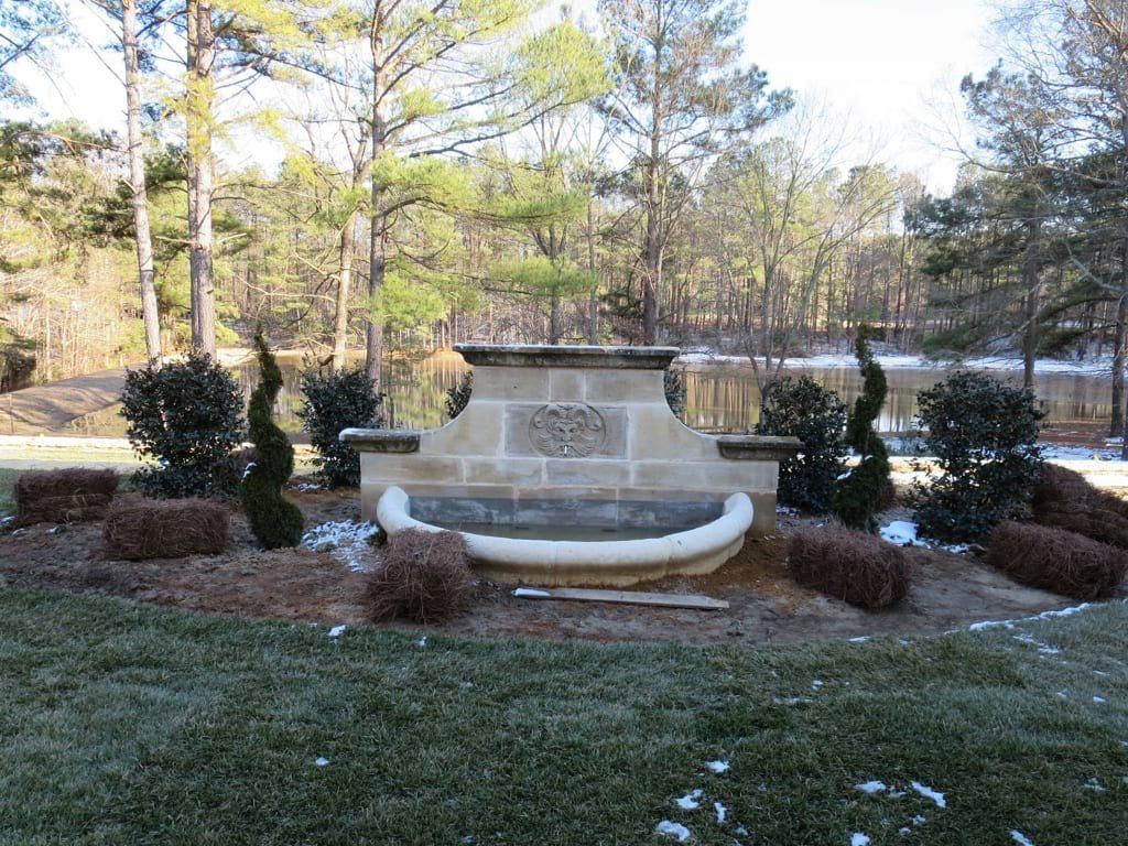 A fountain is sitting in the middle of a lush green field