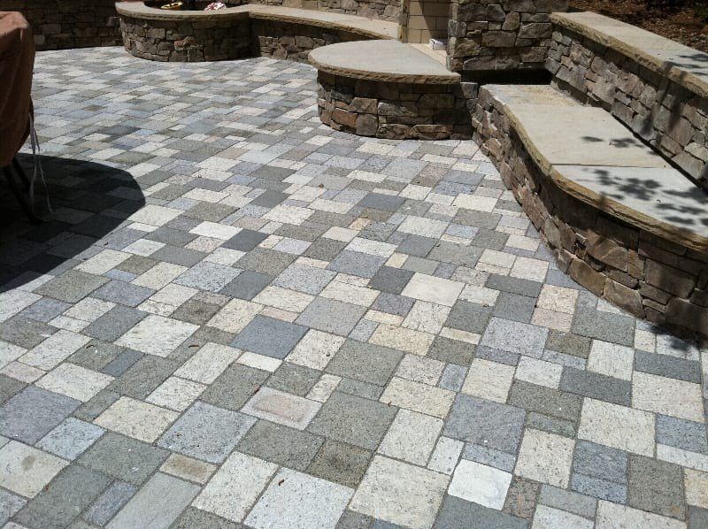 A patio with bricks and a stone wall