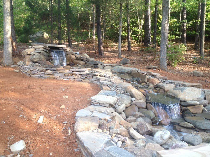 A waterfall is surrounded by rocks in the middle of a forest
