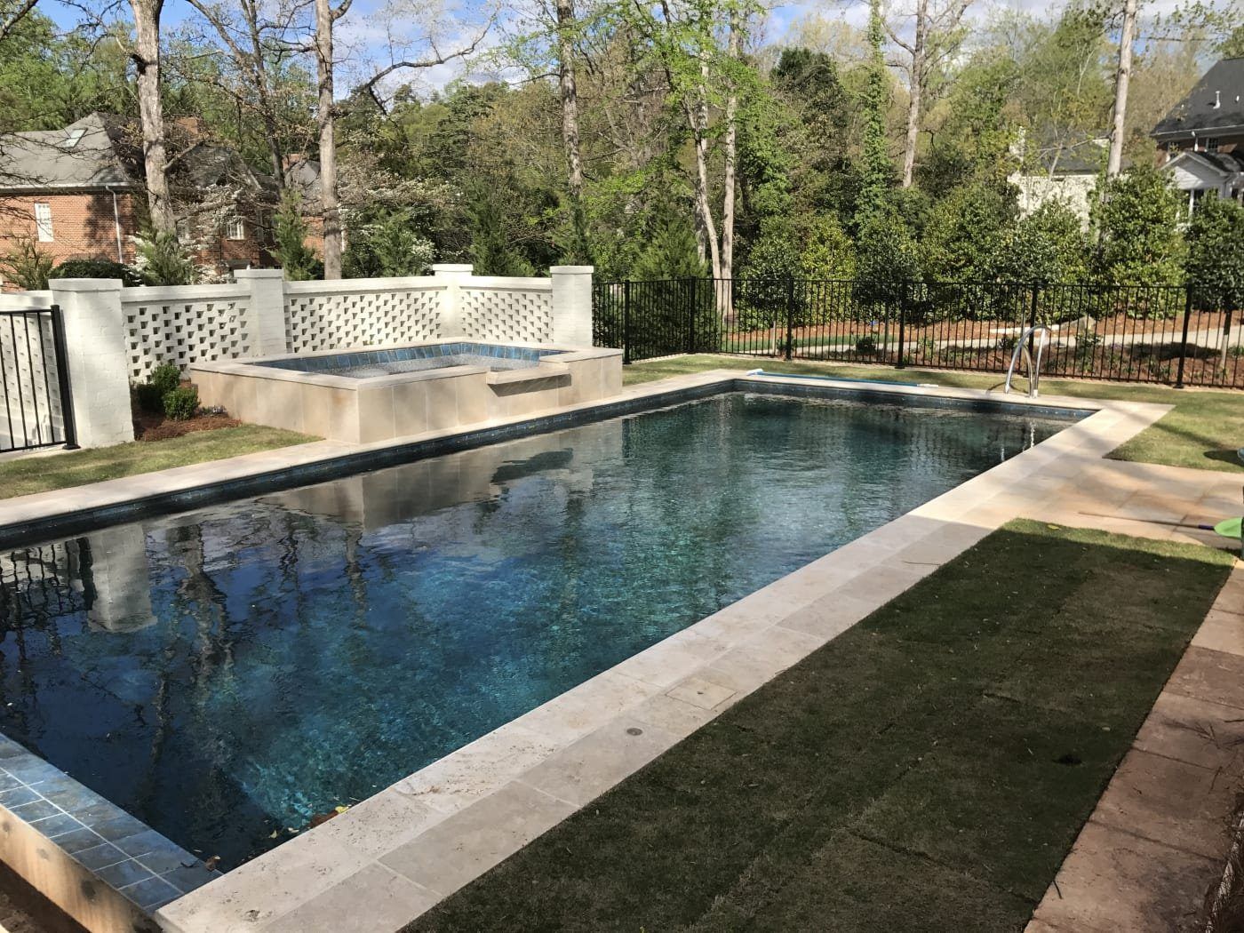 A large swimming pool with a hot tub in the backyard of a house