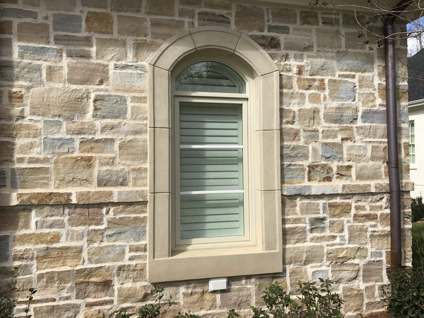 A stone wall with a window in the middle of it