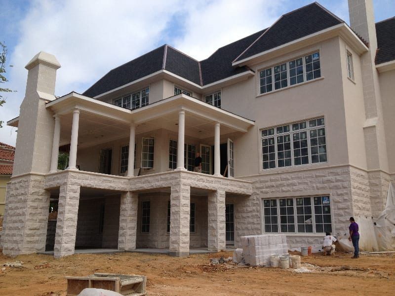 A large white house with a black roof is under construction