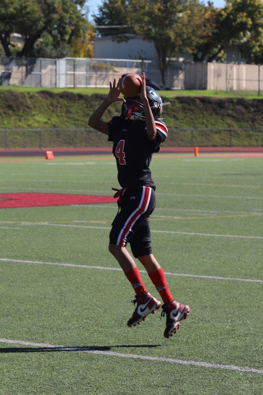 Football player in black uniform catching a pass on a field