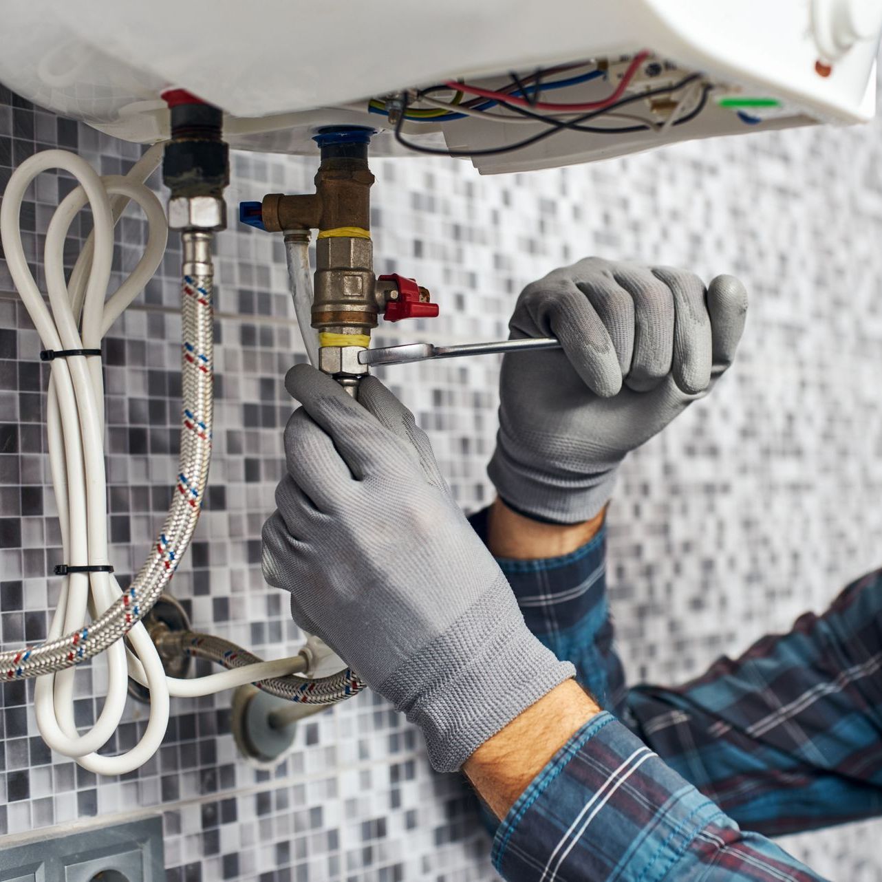 a man is fixing a water heater in a bathroom .