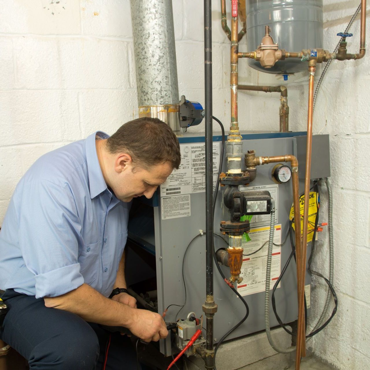 a man is working on a water heater in a basement