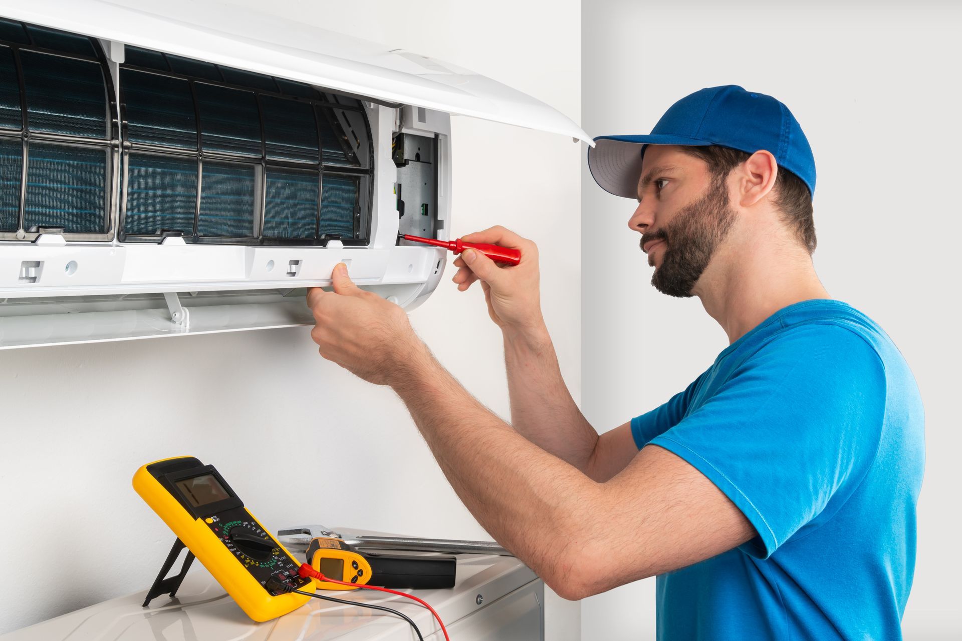 a man is fixing an air conditioner with a screwdriver .