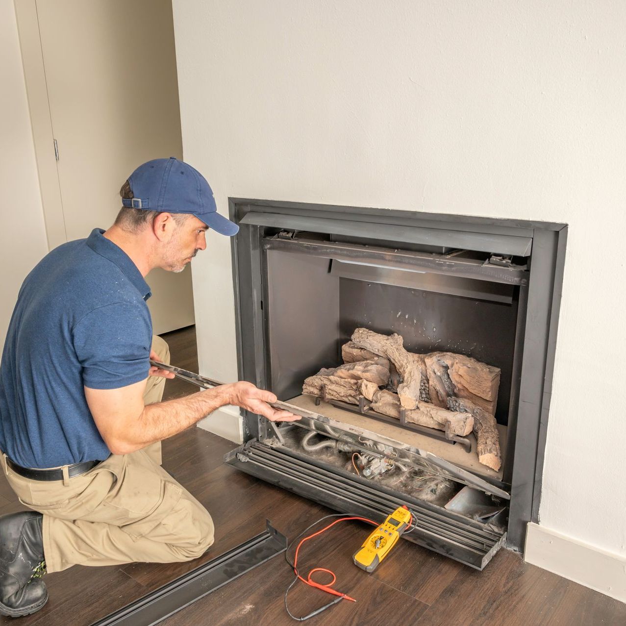 a man is kneeling down in front of a fireplace in a living room .